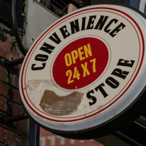convenience store sign open 24/7 on brick wall