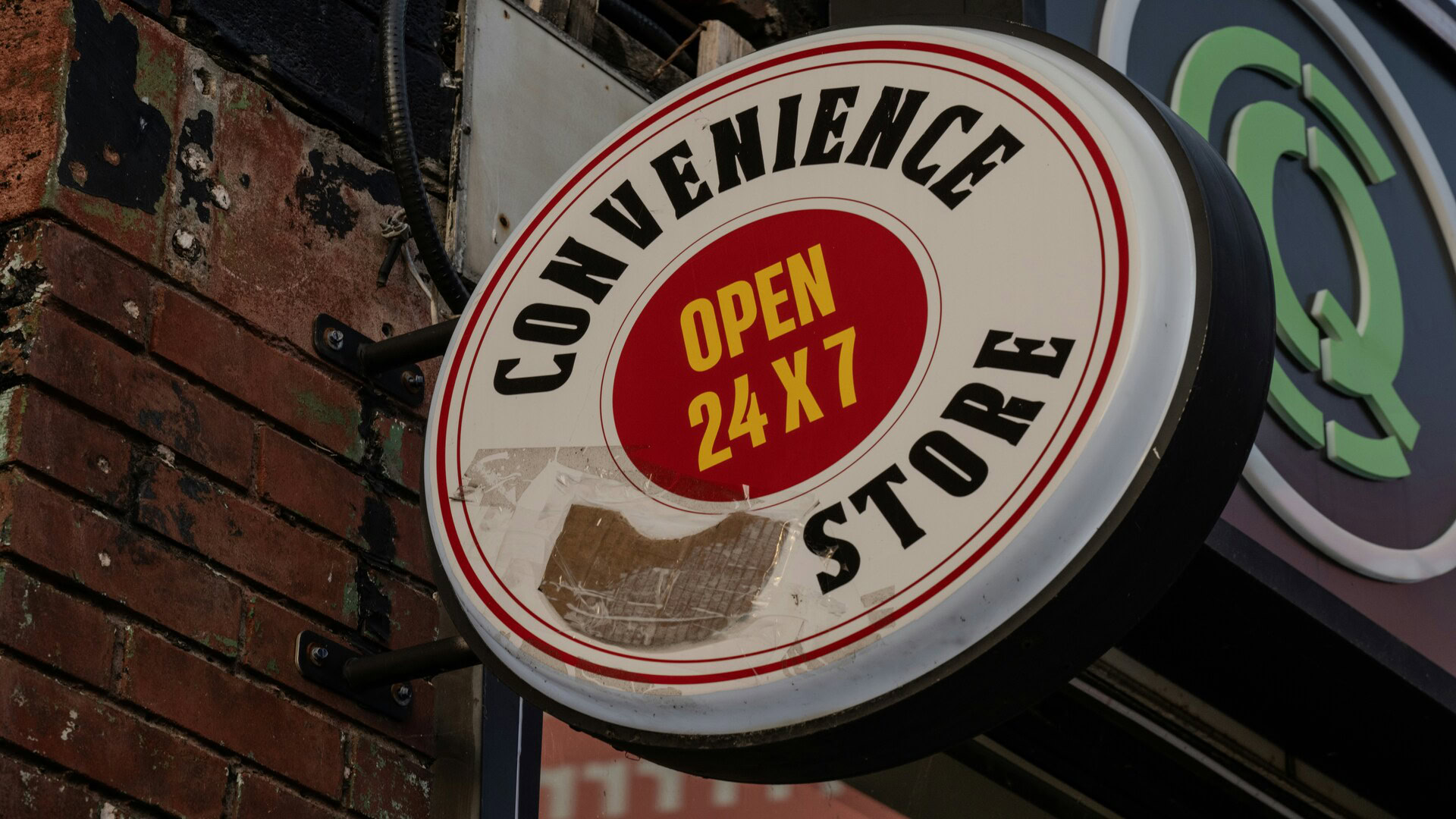 convenience store sign open 24/7 on brick wall