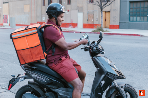delivery rider checks app on black scooter
