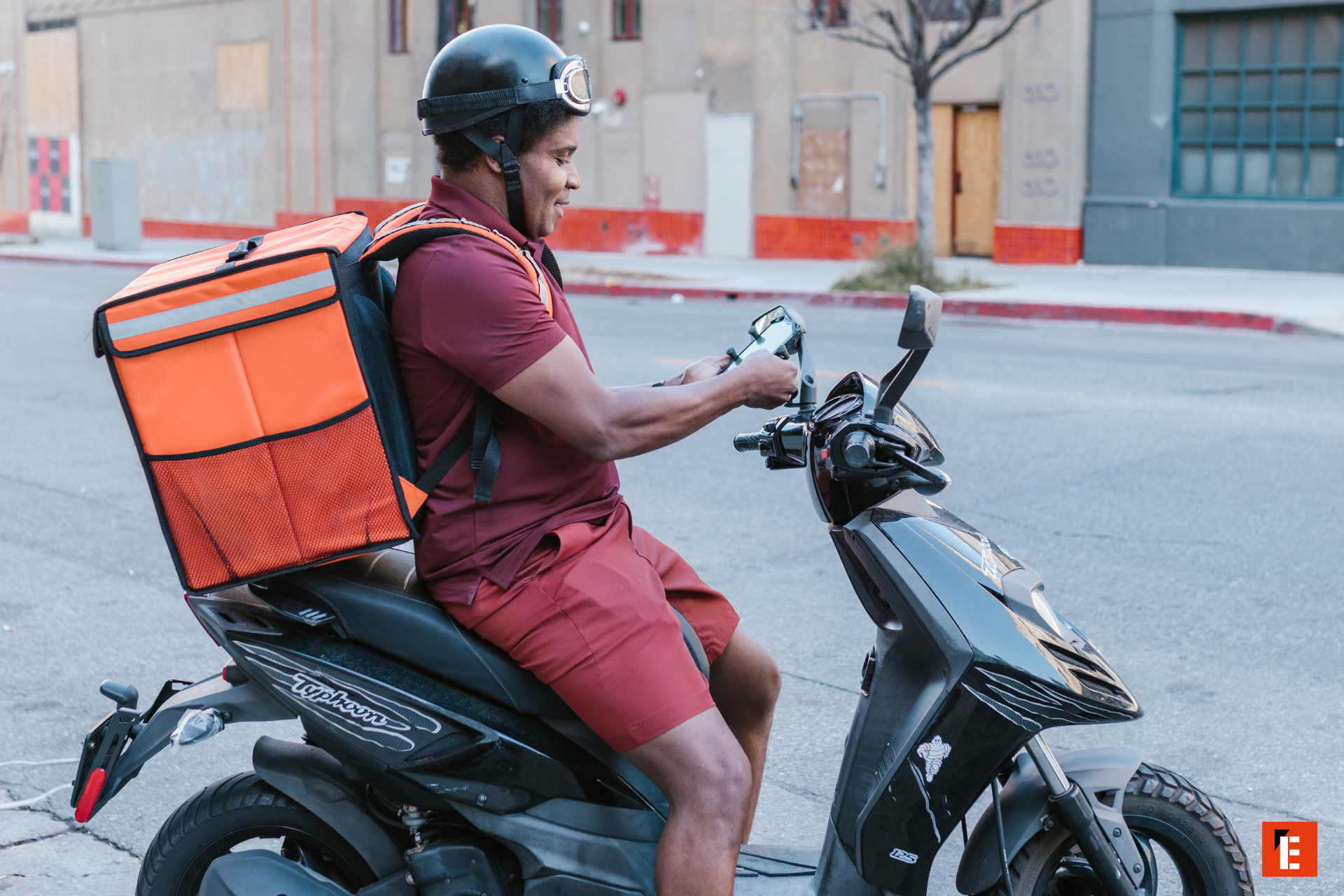 delivery rider checks app on black scooter