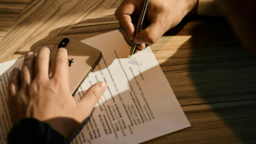 signature de contrat avec smartphone doré et main écrivant