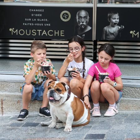 enfants et bulldog devant un glacier en ville