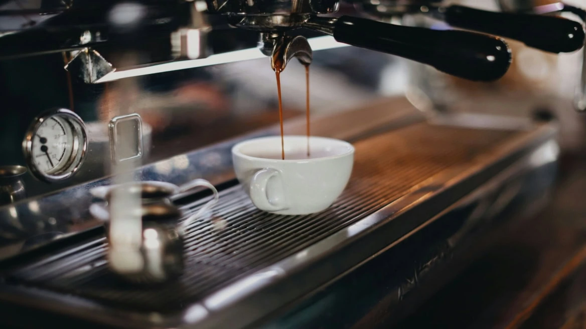 espresso machine brewing coffee into white cup