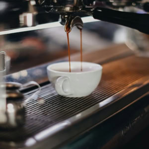 espresso machine brewing coffee into white cup