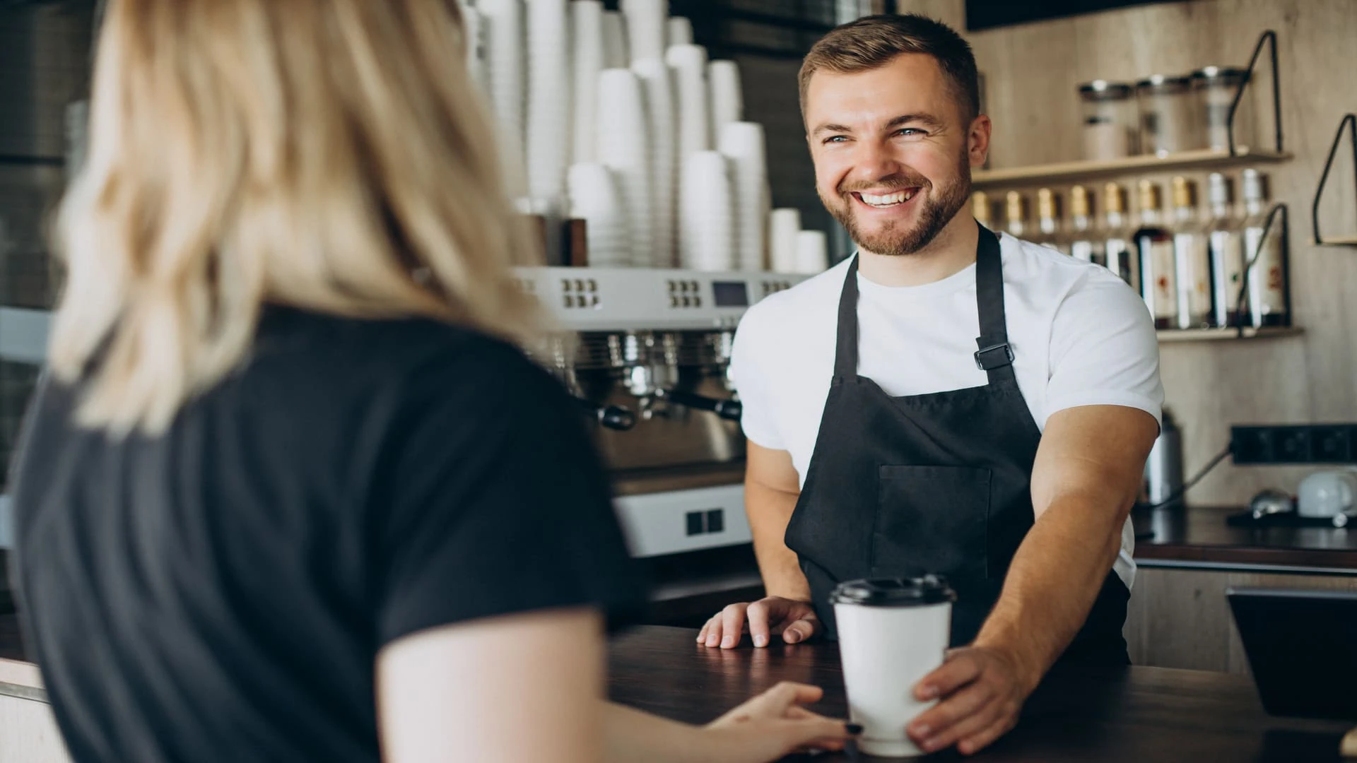 friendly café barista handing coffee to customer