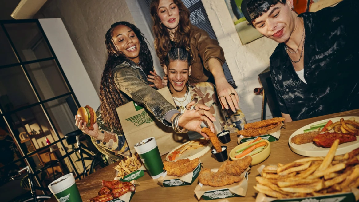 groupe d’amis gourmands autour de fast food Wingstop