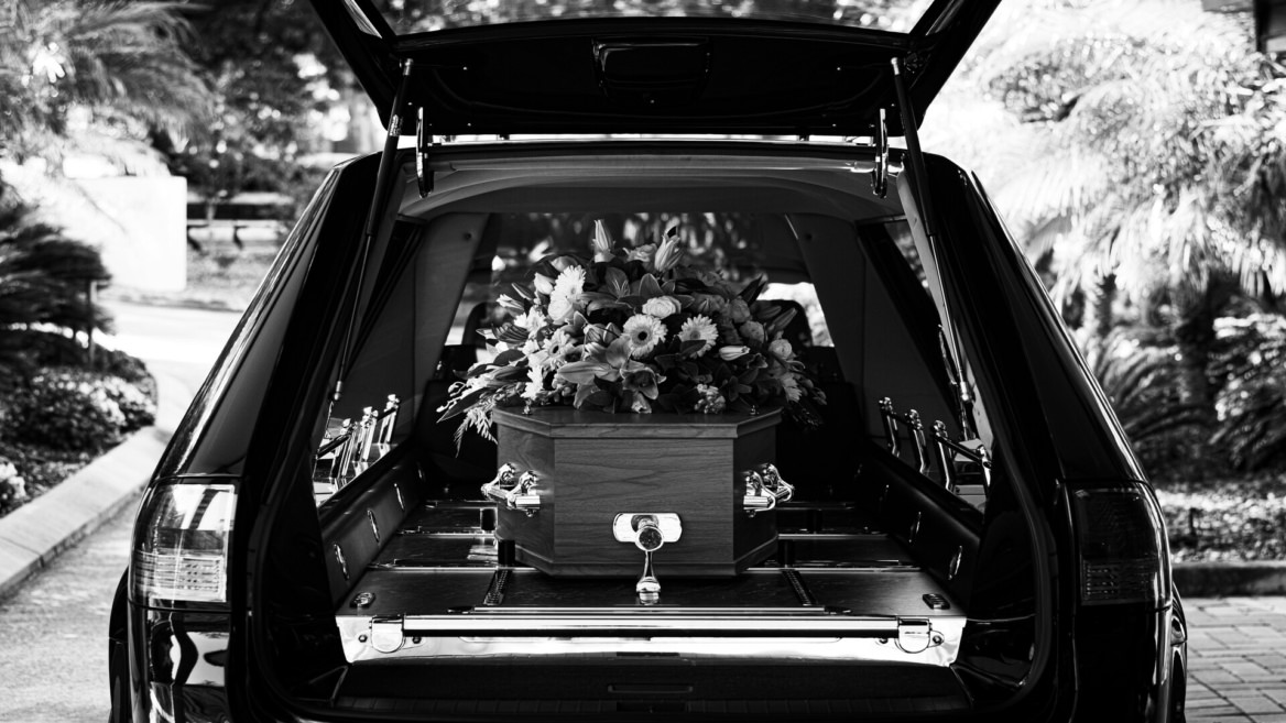 cercueil fleuri dans un corbillard noir