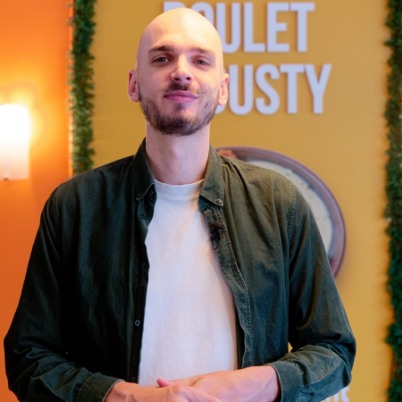homme barbu en interview devant fond coloré