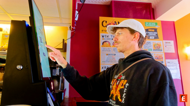 homme commandant sur kiosque tactile au restaurant
