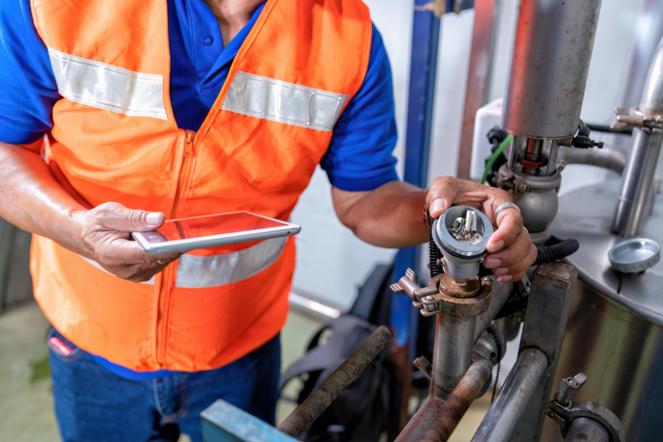 technicien de maintenance avec tablette et pièce mécanique
