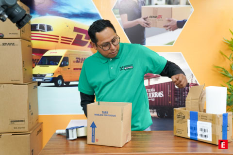 empleado dhl empaquetando paquetes en mesa logística