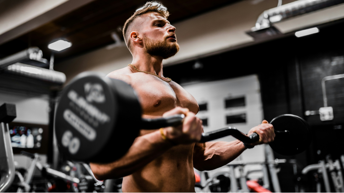 muscular man curling ez bar in gym