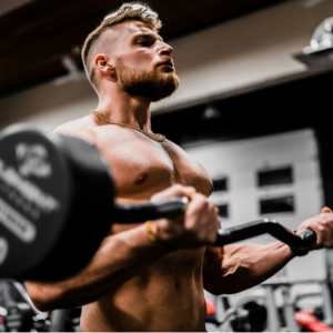 muscular man curling ez bar in gym