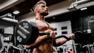 muscular man curling ez bar in gym
