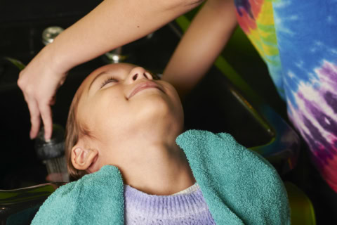 niña relajada recibiendo lavado de cabello en salón