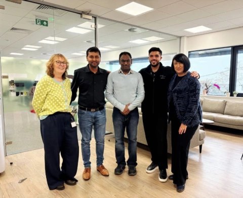 five colleagues posing in a modern office lounge