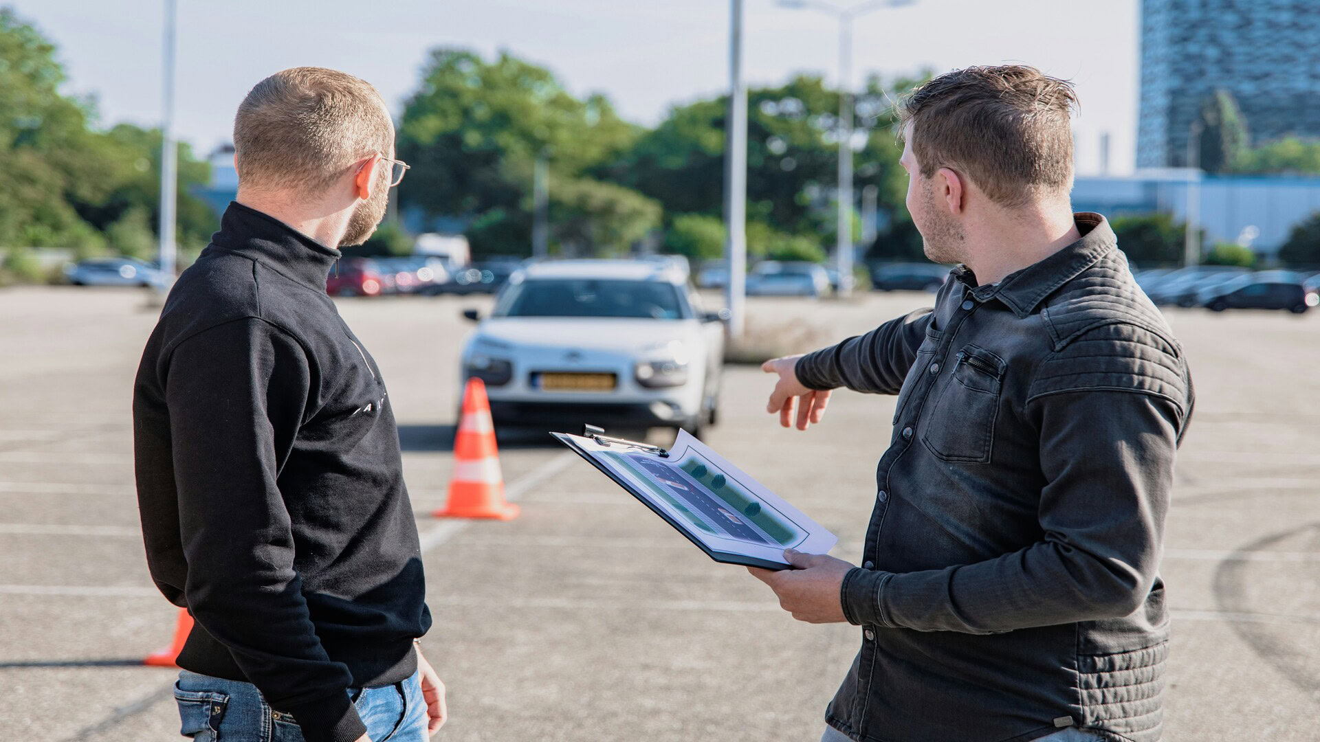 two men inspect white car in parking lot