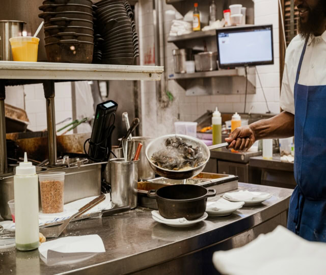 chef preparing steaming mussels in a busy kitchen