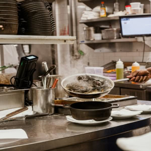 chef plating steaming mussels in busy kitchen