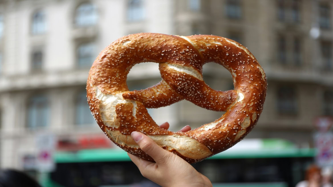 giant salted pretzel held on city street