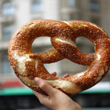 giant salted pretzel held on city street