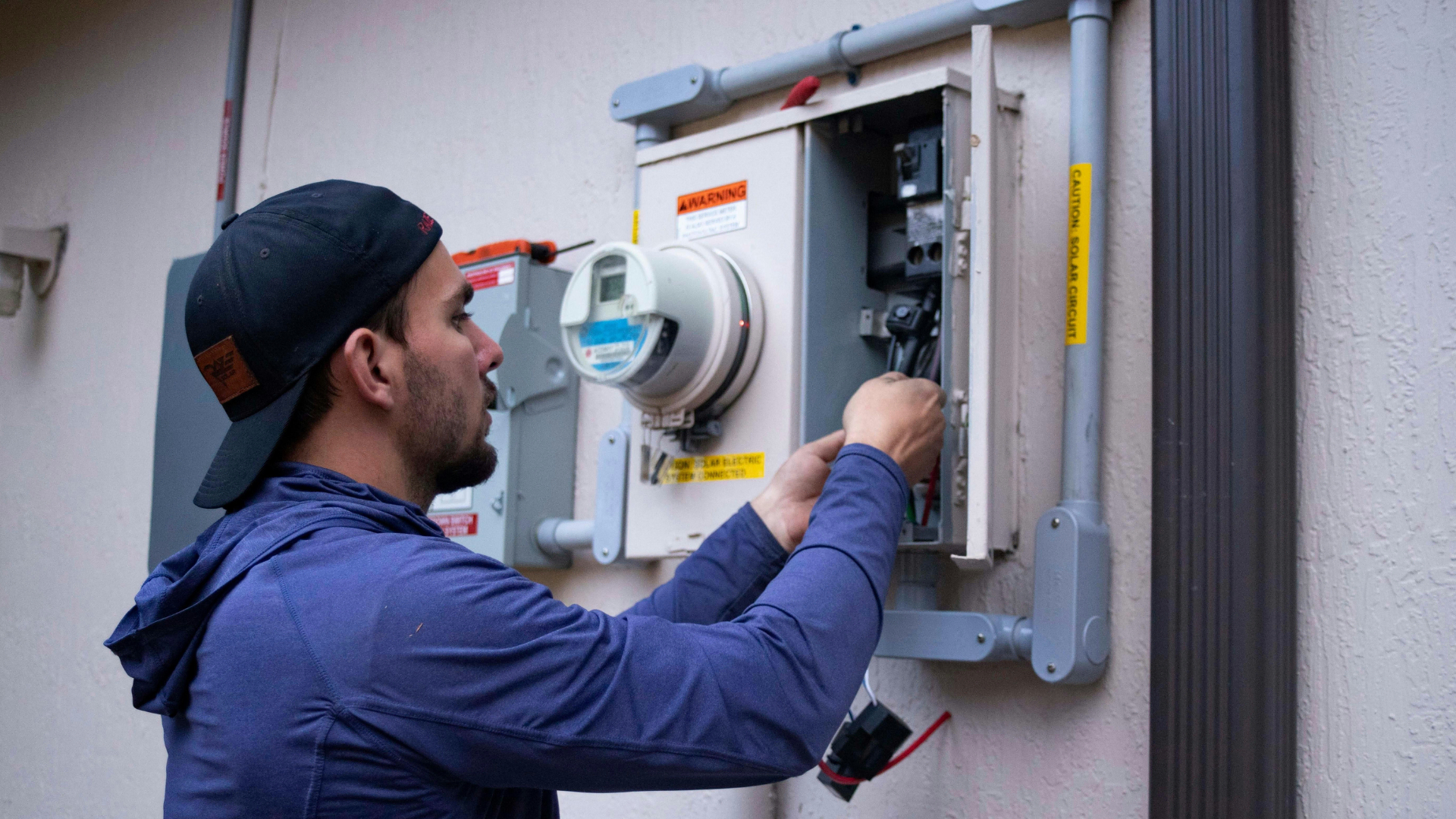 solar electrician repairing outdoor utility panel