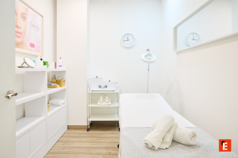 cabina de estética blanca con camilla y lámpara