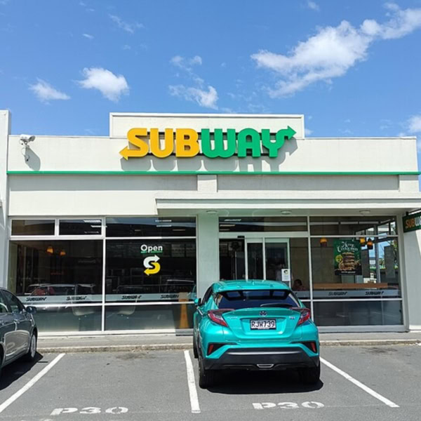 façade d’un subway au soleil, avec stationnement