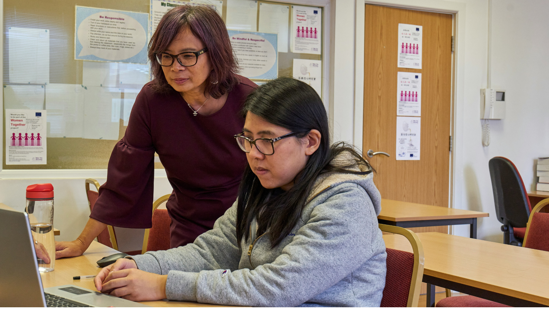 women collaborating at laptop in classroom