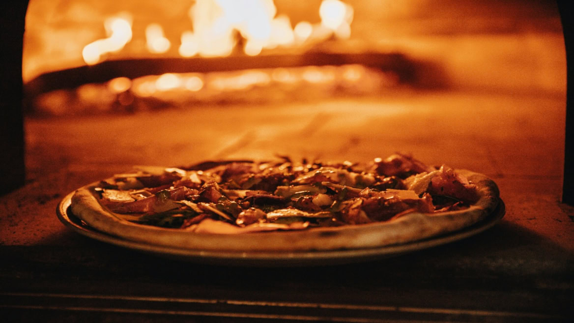 wood fired pizza baking in a glowing oven