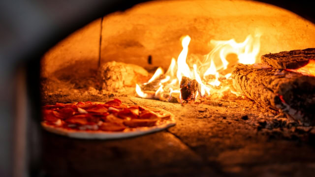 wood fired pizza baking in flames