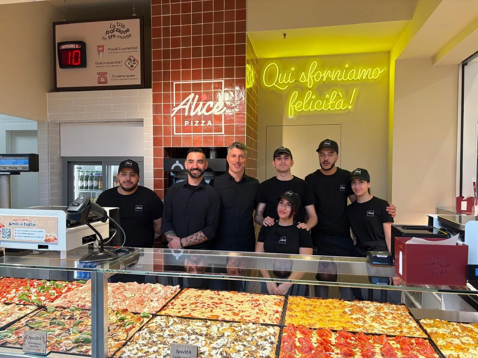 team alice pizza sorridente al banco con pizze fresche