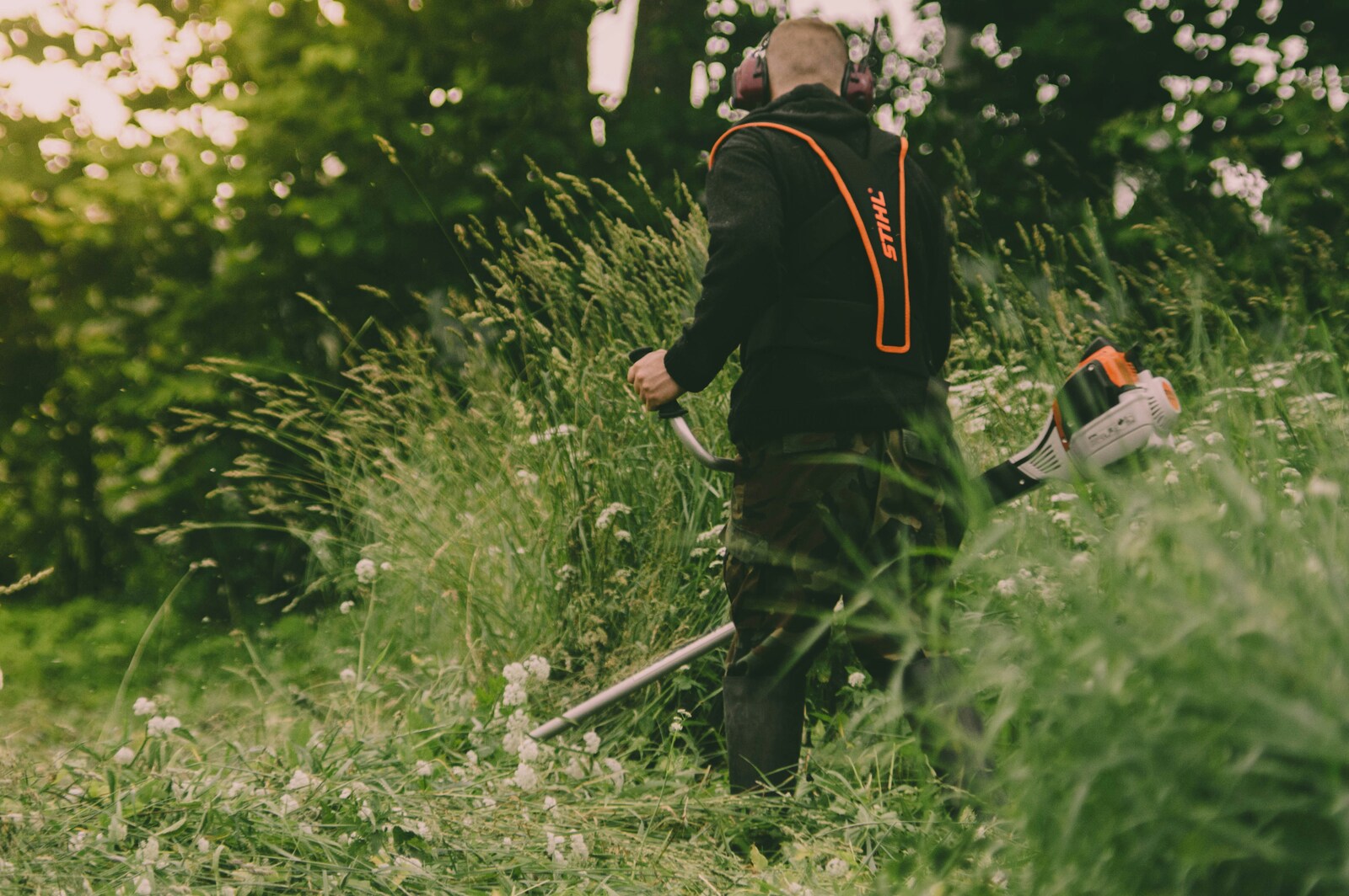 worker cutting tall grass with brush cutter
