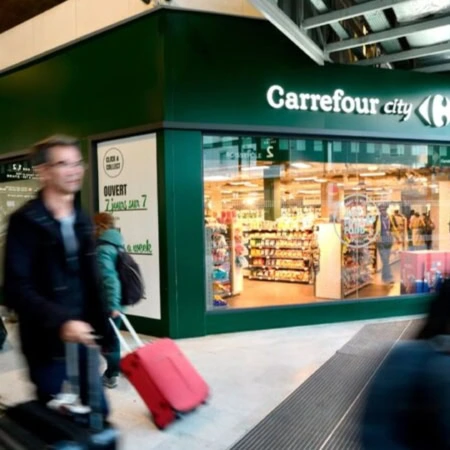 carrefour city en gare, passants flous et valise rose