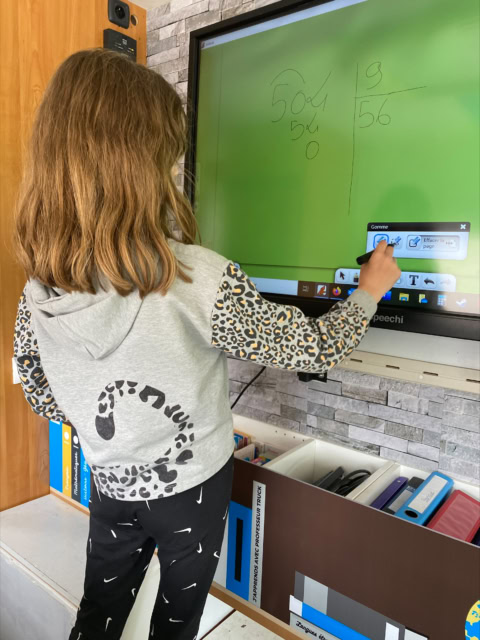 enfant résolvant des maths sur tableau interactif