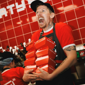 fast food worker carrying a tower of takeaway boxes