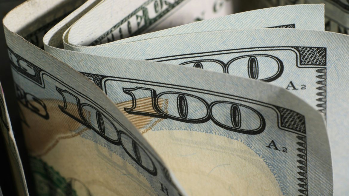 close up of folded $100 bills and blue security patterns