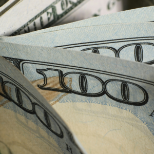 close up of folded $100 bills and blue security patterns