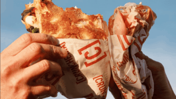 mani con grande kebab avvolto al cielo blu