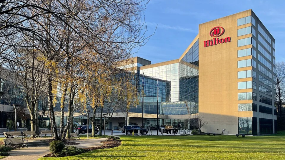 hilton hotel exterior with glass tower and lawn