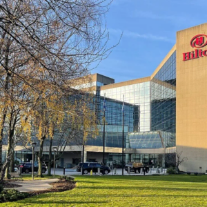 hilton hotel exterior with glass tower and lawn