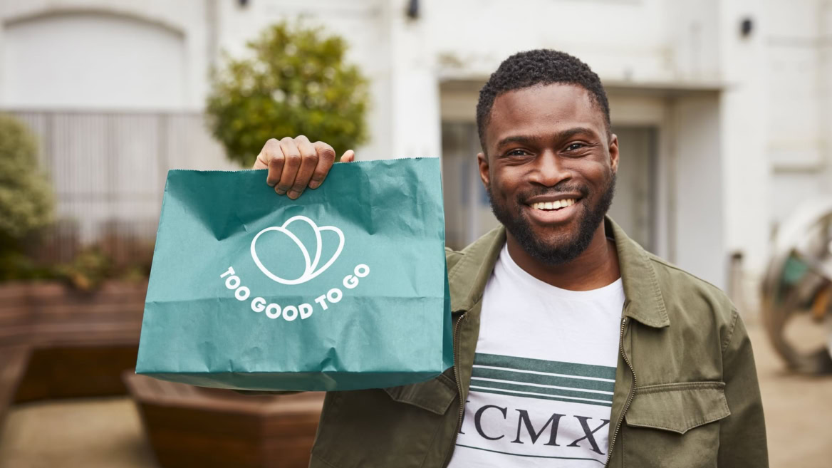 homme souriant tenant un sac too good to go