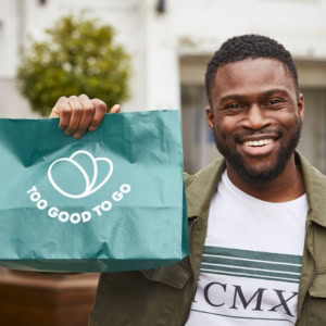 homme souriant tenant un sac too good to go