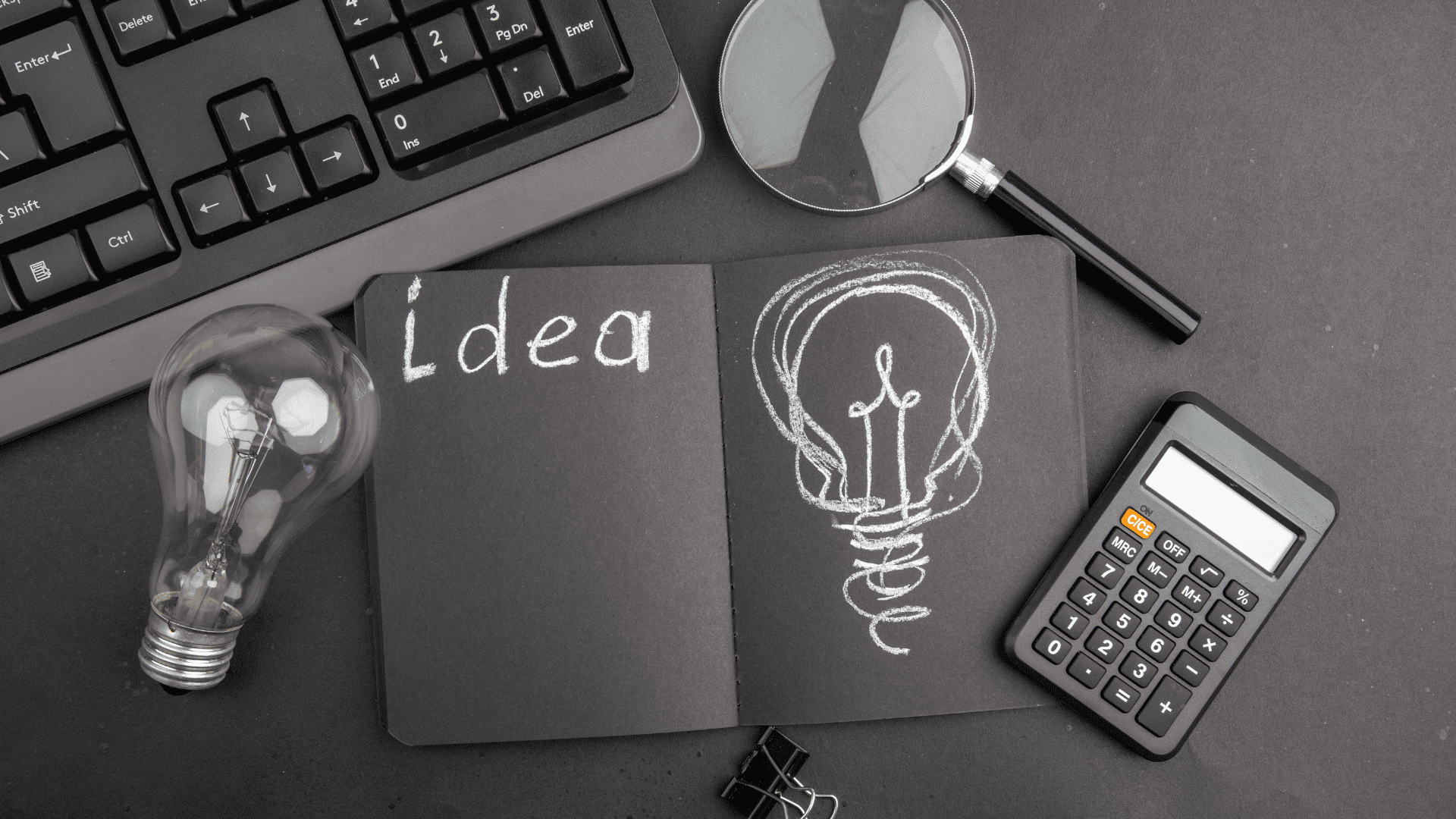 cuaderno de ideas con bombilla y lupa