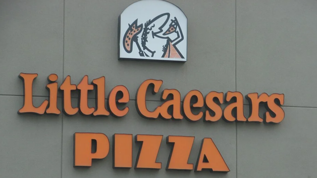 little caesars pizza storefront sign on gray wall