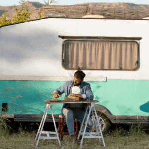 hombre trabajando junto a caravana vintage en el campo