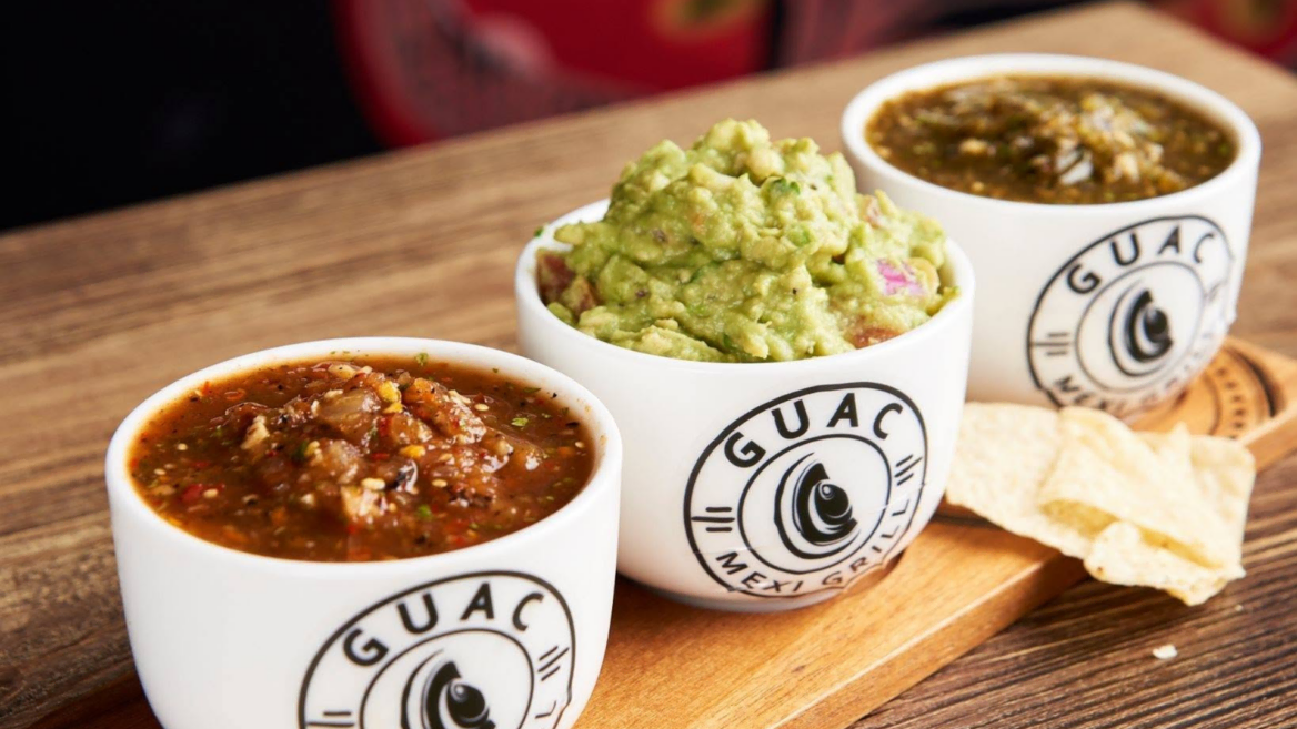 mexican salsa and guacamole cups on wood board