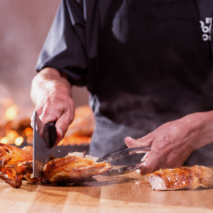 carving roasted chicken on a wooden board