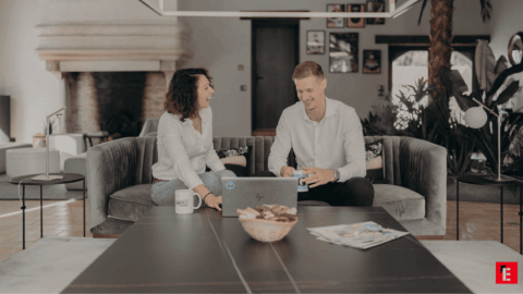 couple souriant devant un ordinateur portable dans le salon