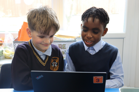 two schoolboys collaborating on a laptop